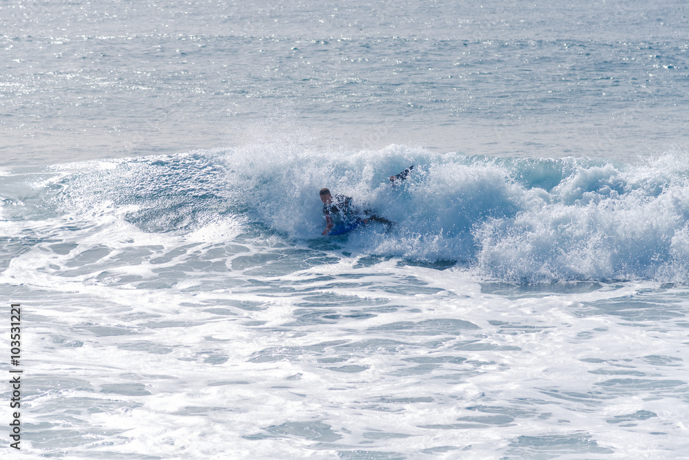 Obraz premium Bodyboarding and surfing in the waves of the Atlantic in front of the island La Gomera. A short light type of surfboard ridden in a prone position