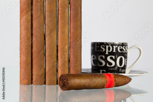 Different cigars and cup of coffee on a  glass table