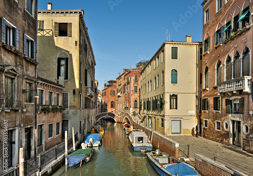 typical canal with old colorful brick houses and boeats in Venice, Italy, Europe 