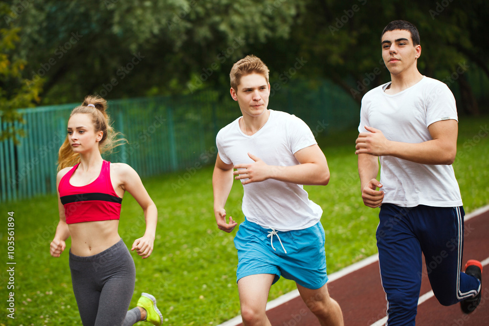 Running athletes at stadium.