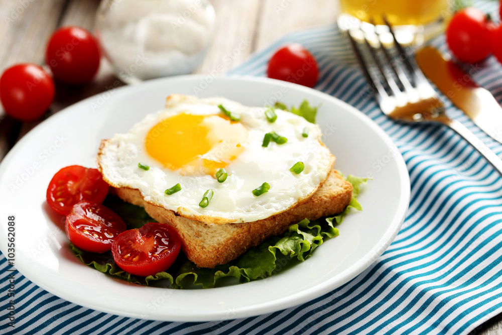 Fried eggs with toasts on plate on grey wooden table Fried eggs with toasts on plate on grey wooden table