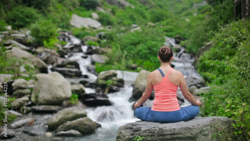 Woman meditating at tropical waterfall Woman meditating at tropical waterfall