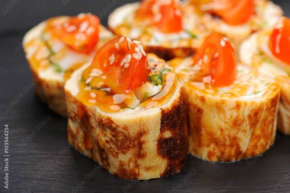 Set of fusion japanese rolls with omelette and tomatoes on black Set of fusion japanese rolls with omelette and tomatoes on black