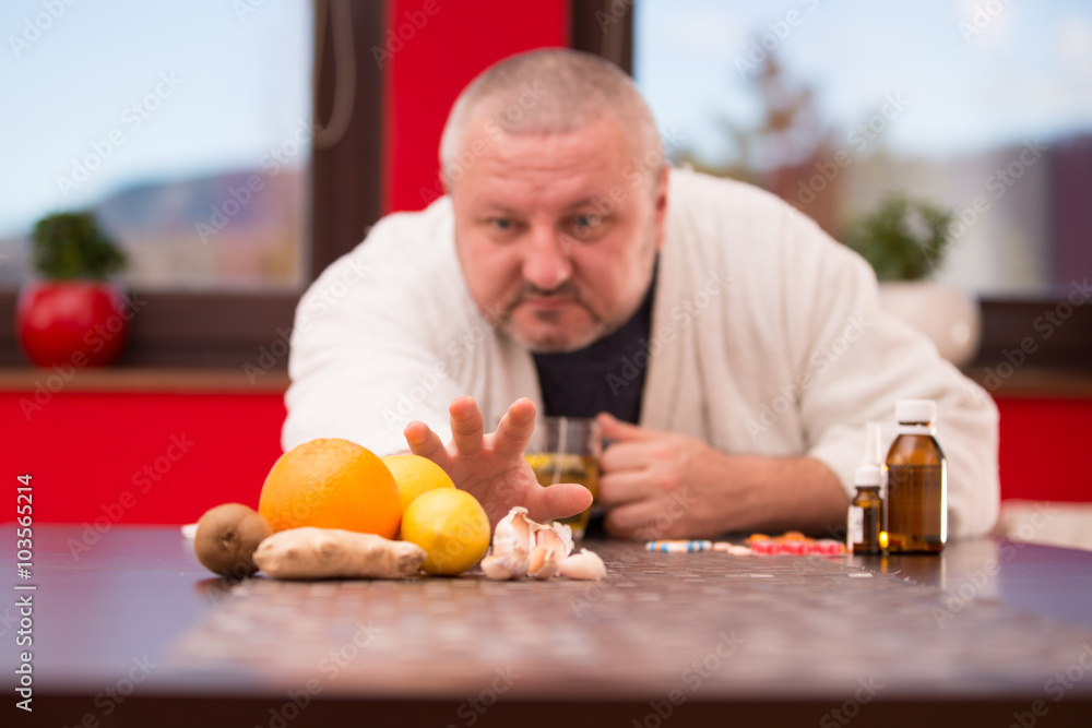 Fototapeta premium Sick man suffering cold and winter flu virus drinking tea
