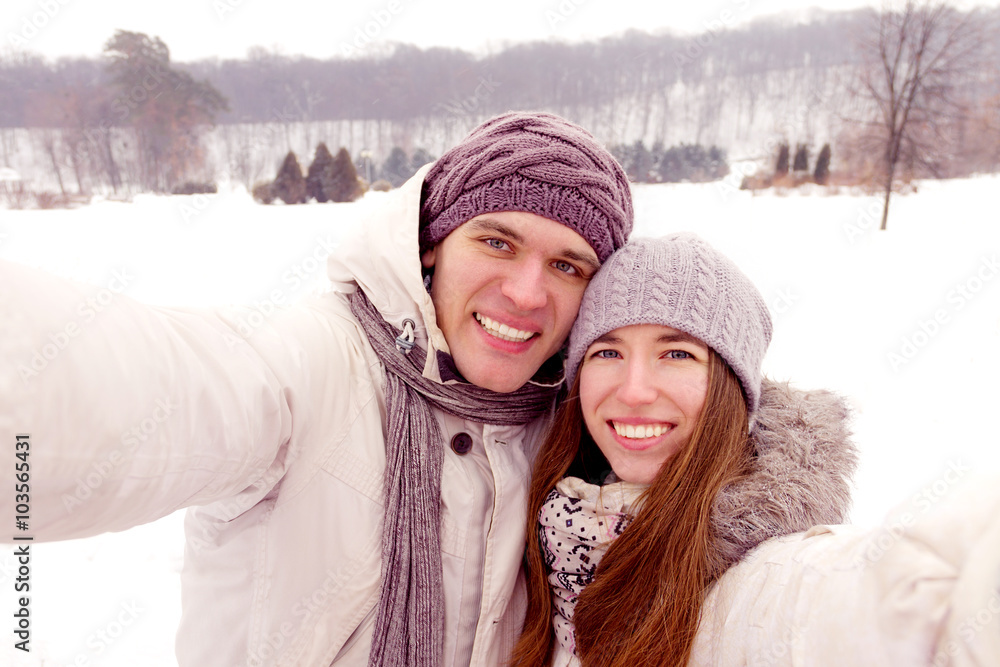 Happy couple doing selfie on a date in park in winter