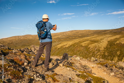 hiker taking photo of mountain landscape with smartphone