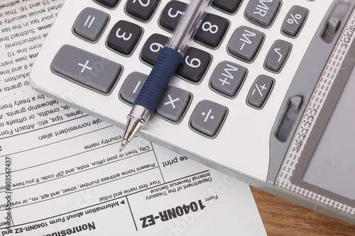 Calculator and pen on tax form Background