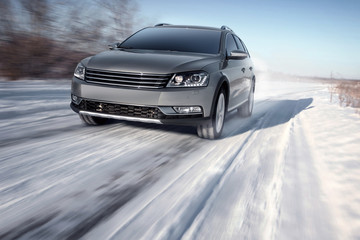 Gray modern car drive speed on road at winter daytime