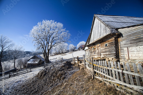 Winter rural landscape with cottage on the hill