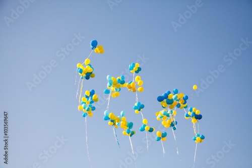 Bright colorful inflatable balloons up in air over blue sky background.