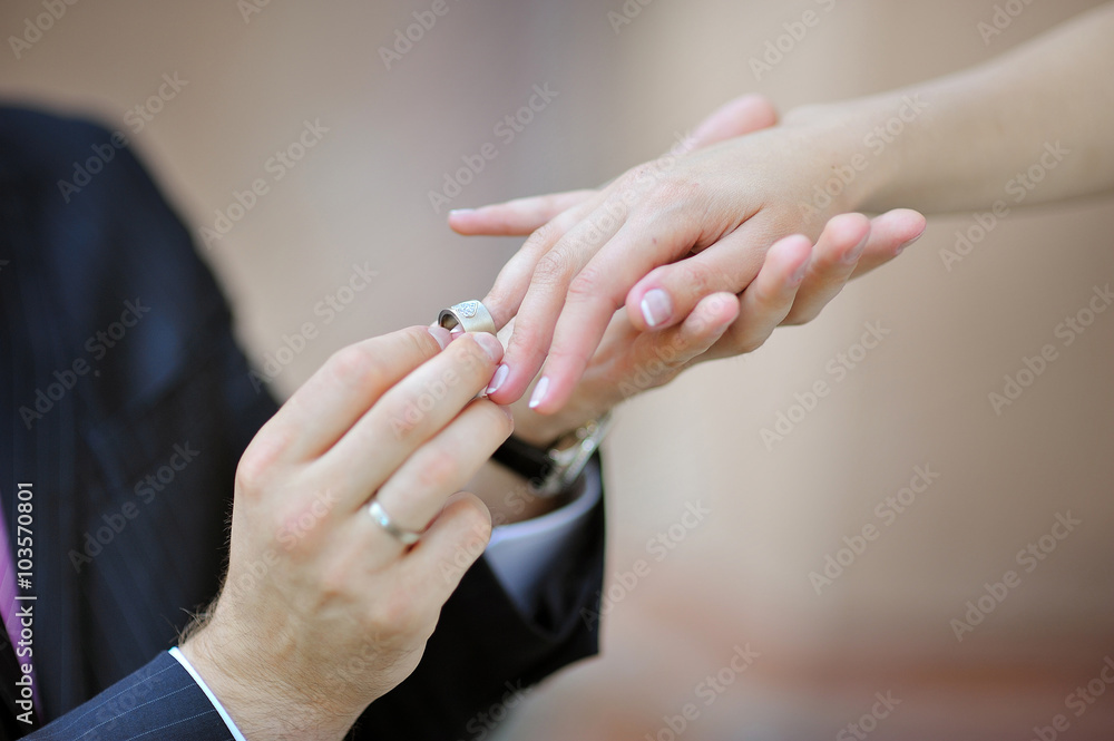 groom's hand putting a wedding ring on the bride's finger