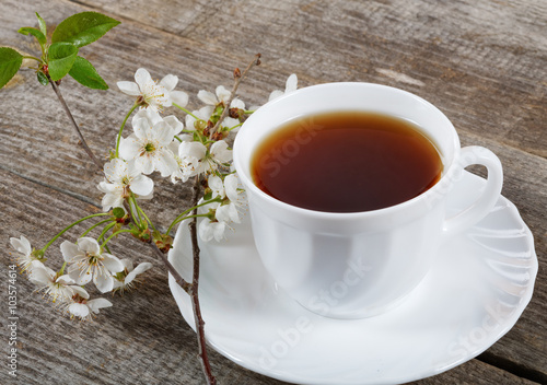 White cup of tea with flowers of a cherry