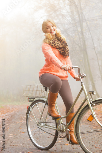 Happy active woman riding bike in autumn park.