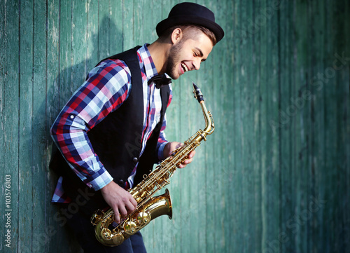 Photography Young man playing on saxophone outside near the old wall