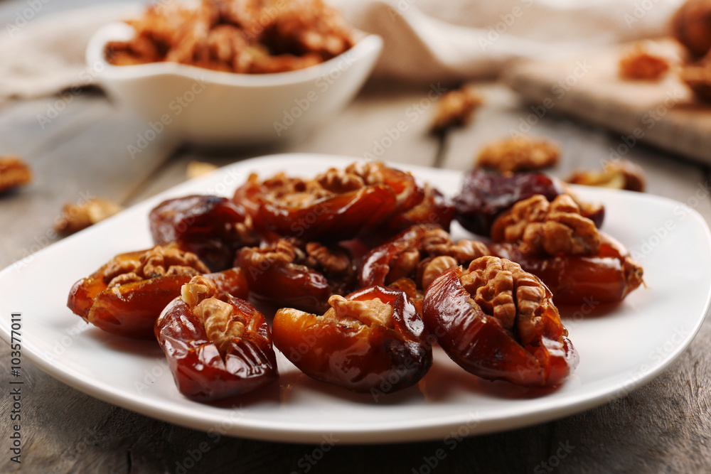 Walnut and date fruit in plate on wooden table, close-up Walnut and date fruit in plate on wooden table, close-up