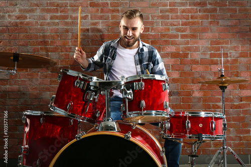 Musician playing the drums on brick wall background