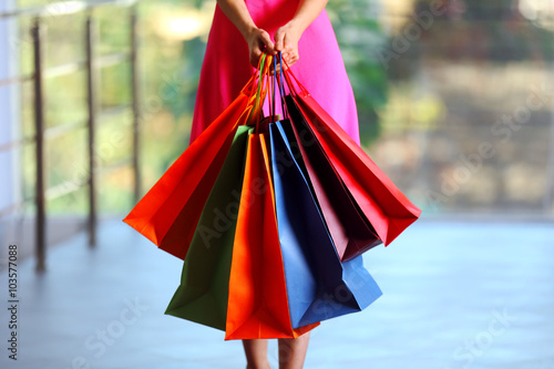 Young woman with shopping packages on defocused background