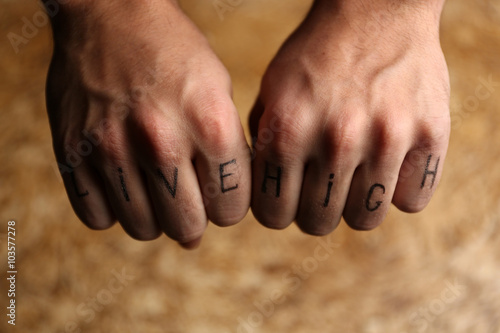 Tattoo inscriptions on male fingers drawn with marker © Africa Studio