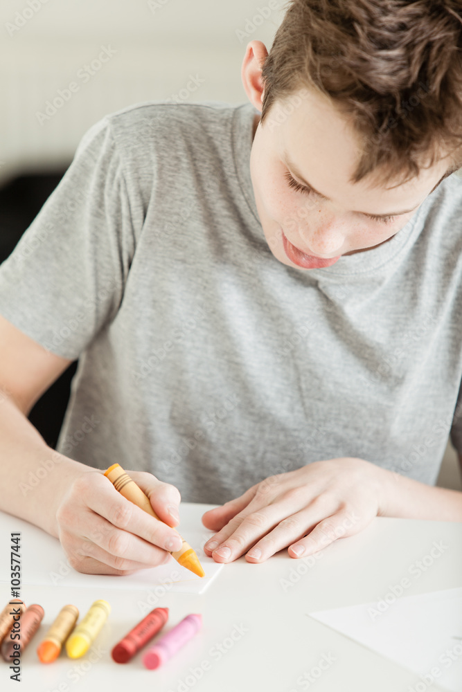 Male Teenager Making Art on Paper Using Crayons Male Teenager Making Art on Paper Using Crayons