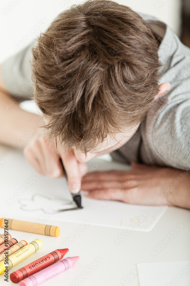 Serious Boy Coloring his Drawing on a White Paper Serious Boy Coloring his Drawing on a White Paper