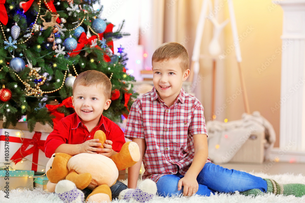 Two cute small brothers with teddy bear on Christmas tree background Two cute small brothers with teddy bear on Christmas tree background