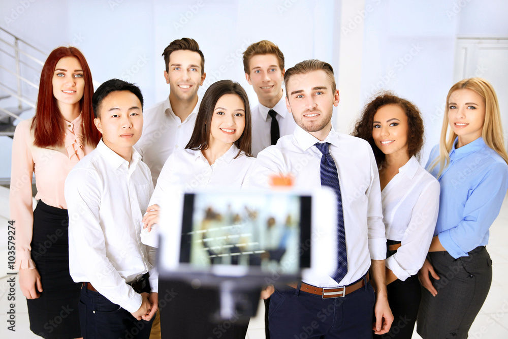 Young people making group photo with smart phone in office Young people making group photo with smart phone in office