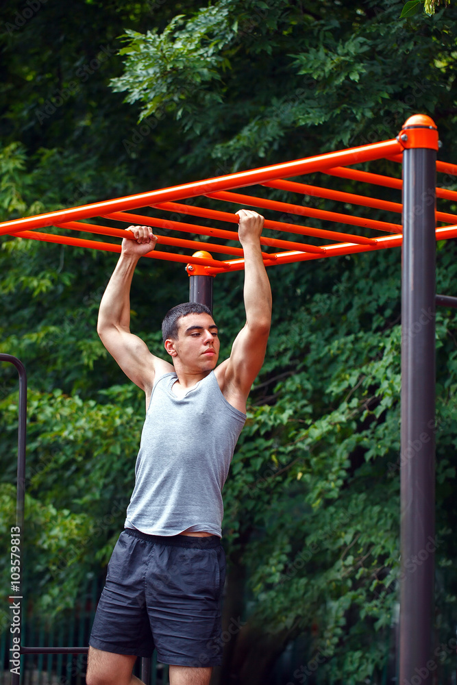 Obraz premium Muscular man doing pull-ups on horizontal bar