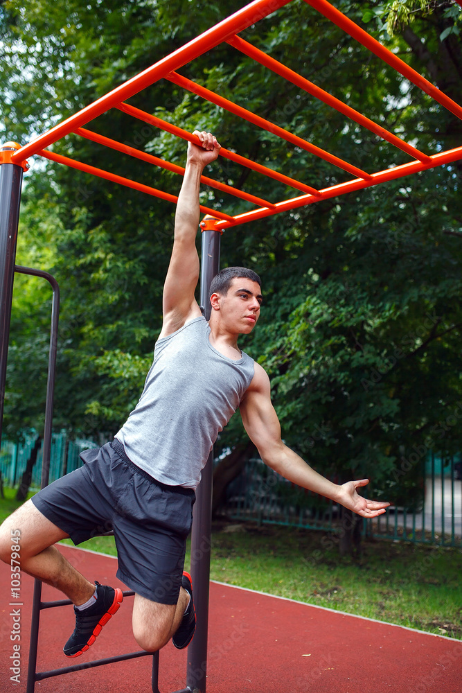 Fototapeta premium Muscular man doing pull-ups on horizontal bar