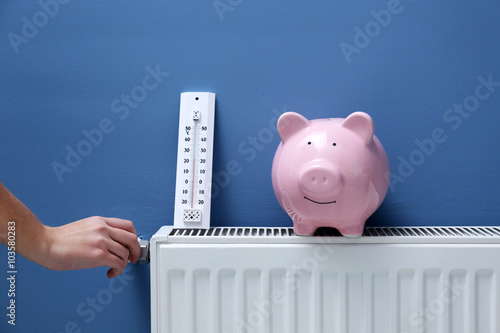 Hand adjusting the temperature on radiator. Saving heating in winter