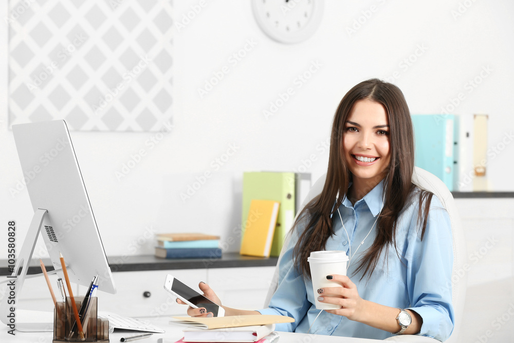 A beautiful successful woman with mobile phone drinking coffee at the modern office A beautiful successful woman with mobile phone drinking coffee at the modern office