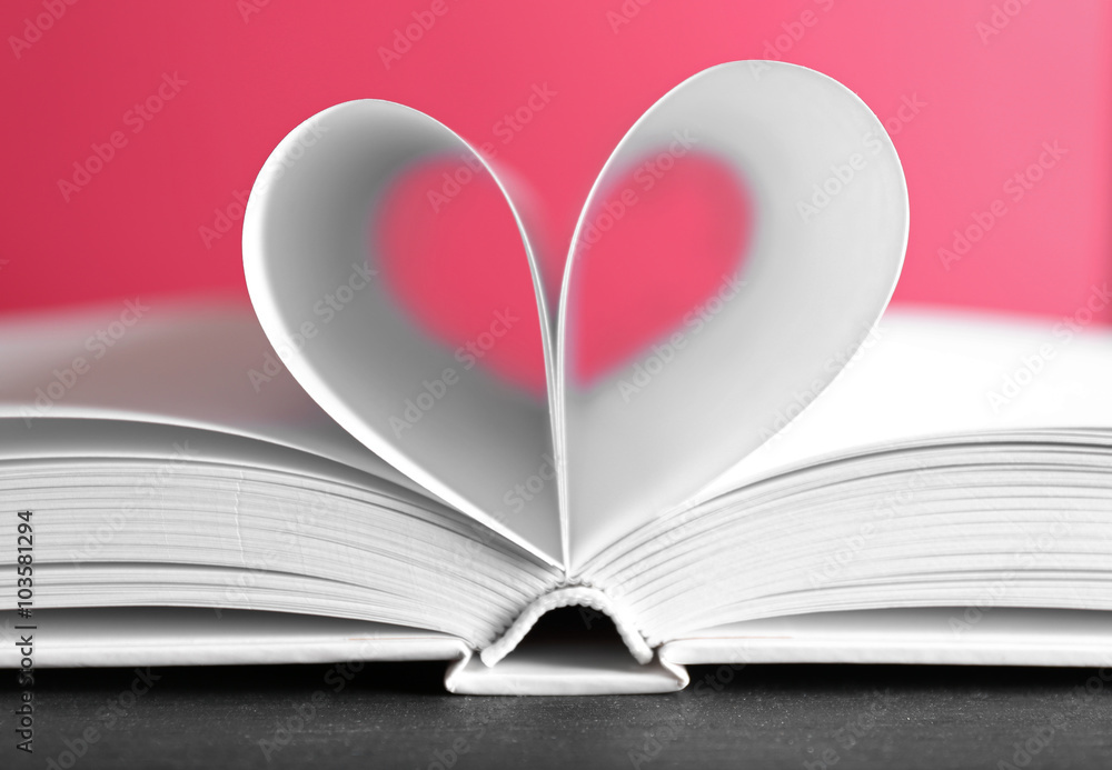 Sheets of book curved into heart shape on pink background Sheets of book curved into heart shape on pink background