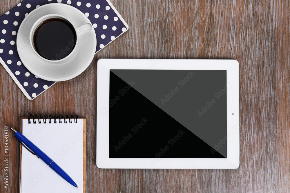 Tablet with cup of coffee and notepad on wooden table Tablet with cup of coffee and notepad on wooden table
