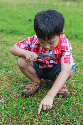 Young boy exploring nature with magnifying glass. Outdoors 