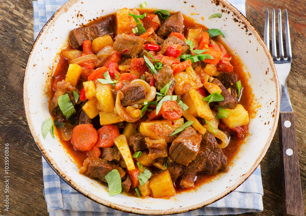 Beef stew with vegetables on a rustic wooden table. Beef stew with vegetables on a rustic wooden table.