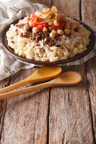 kushari of rice, pasta, chickpeas and lentils close up on the table. vertical
