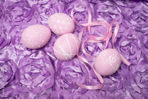 Decorated easter eggs with ribbon on violet fabric background. 