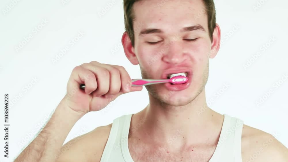 Handsome guy in a white shirt brushing her teeth. The man smiles. Handsome guy in a white shirt brushing her teeth. The man smiles.