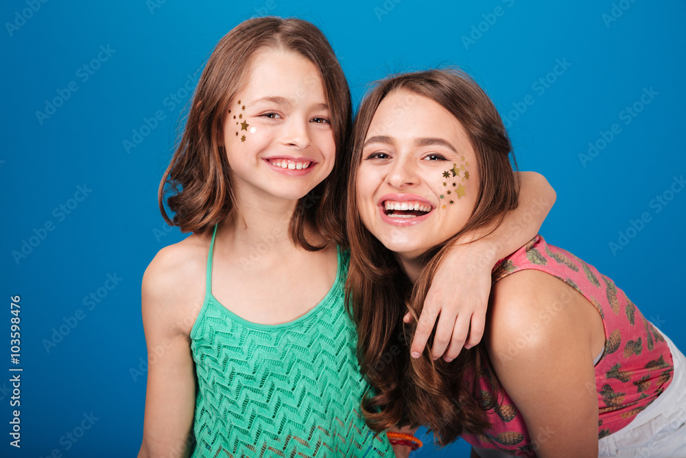 Two happy lovely sisters with decorations on cheeks laughing Two happy lovely sisters with decorations on cheeks laughing