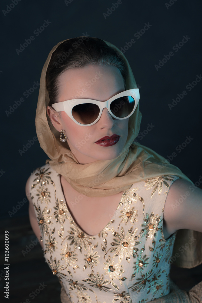 Obraz premium Chique vintage 50s fashion woman wearing sunglasses and scarf ar