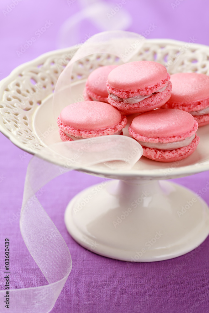 Pink macarons with buttercream filling on cake stand