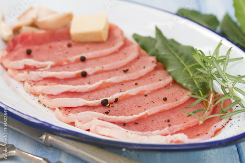 raw pork on dish with herbs