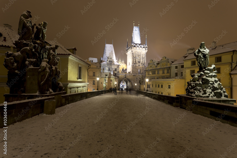 Night snowy Prague Bridge Tower and St. Nicholas' Cathedral from Charles Bridge with its Statues, Czech republic