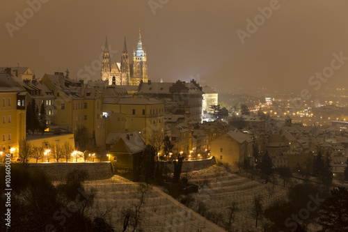 Night snowy foggy Prague City with gothic Castle, Czech republic