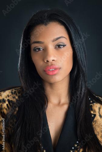 Confident brunette brazilian woman studio portrait against dark background.