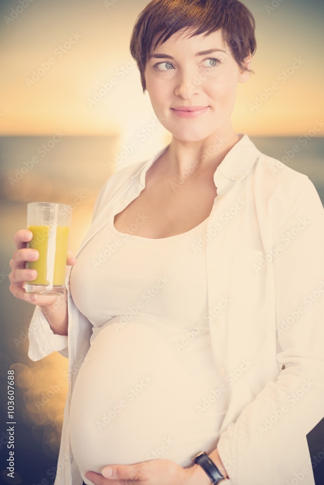 Composite image of pregnant woman holding glass of orange juice Composite image of pregnant woman holding glass of orange juice