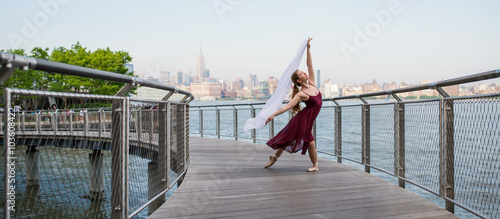 Young beautiful ballerina dancing along New Jersey waterfront with New York as background. photo