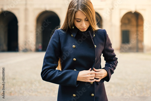 Young woman closing coat outdoors. Parma, Italy. photo