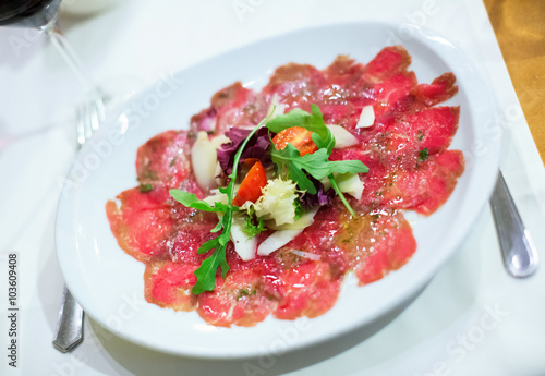 Thin slices of meat carpaccio in white plate