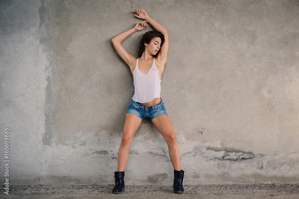Fototapeta premium Sensual young woman full body portrait against grunge wall outdoors.