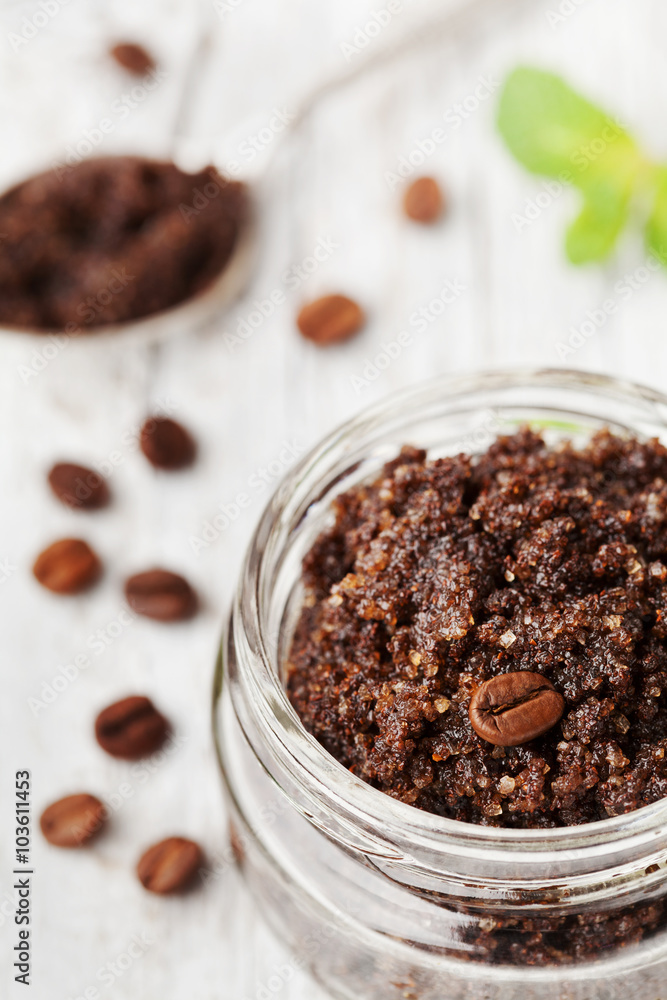 Body scrub of ground coffee, sugar and coconut oil in glass jar on white rustic table, homemade cosmetic for peeling and spa care Body scrub of ground coffee, sugar and coconut oil in glass jar on white rustic table, homemade cosmetic for peeling and spa care